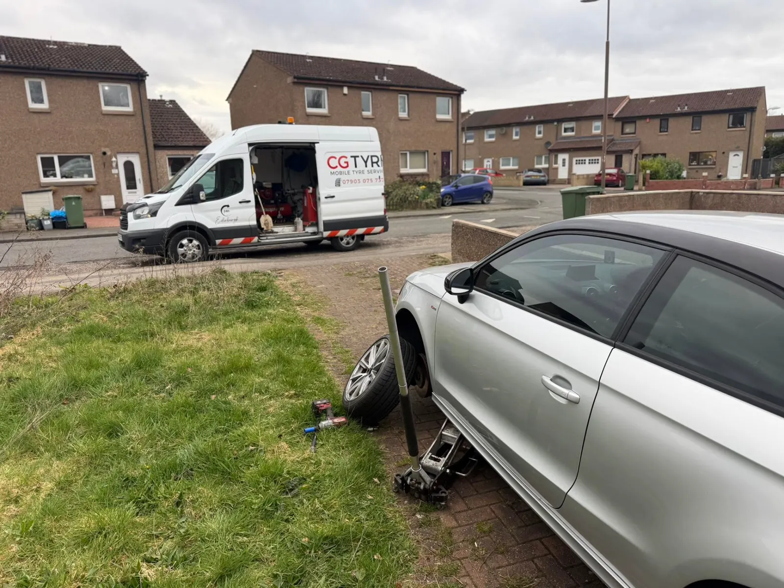 Tyre being changed on a driveway with the CG Tyre van behind